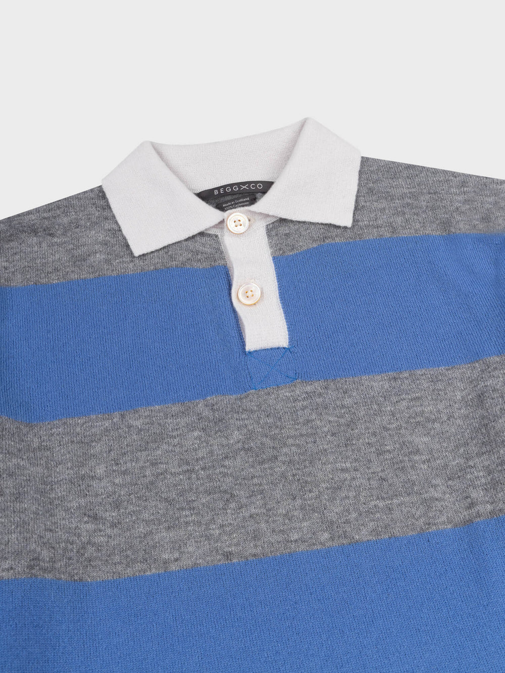 detail of a striped grey and blue cashmere rugby shirt with white collar on a grey background