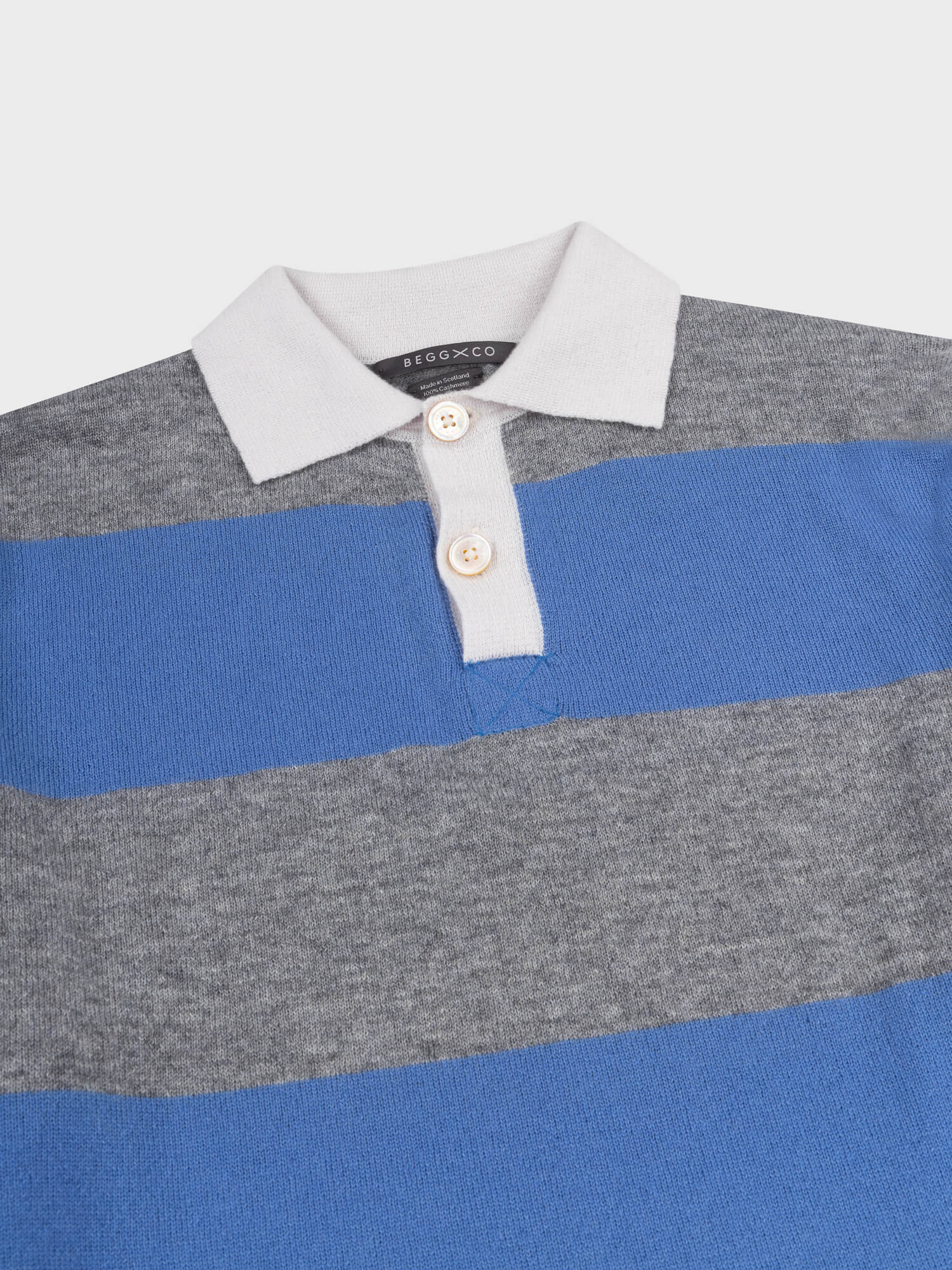 detail of a striped grey and blue cashmere rugby shirt with white collar on a grey background