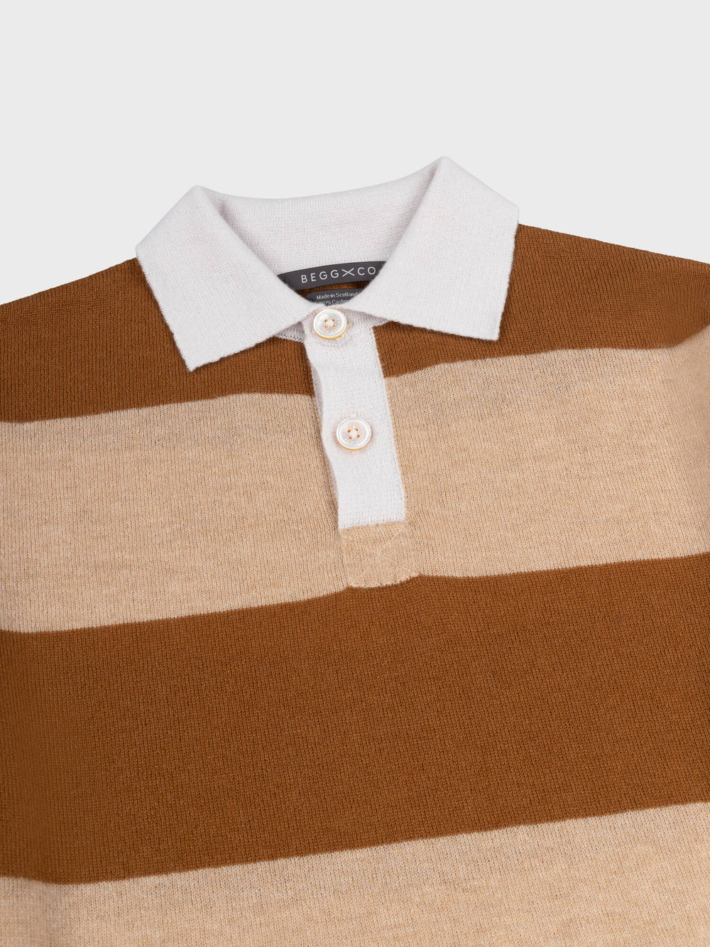 detail of a brown and beige striped cashmere rugby shirt with white collar on a grey background