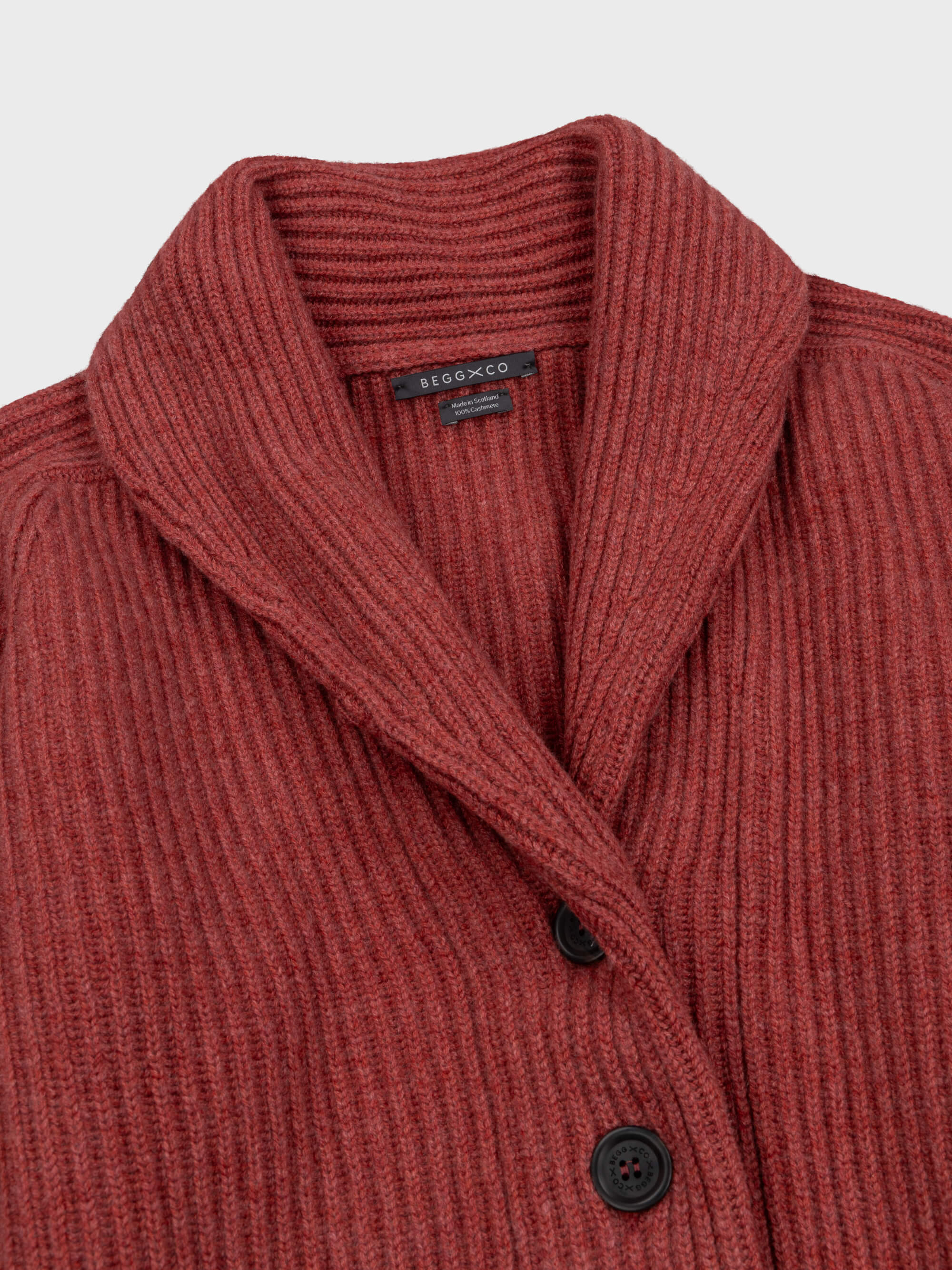 chunky ribbed red cashmere shawl collar detail cardigan with horn buttons on a grey background