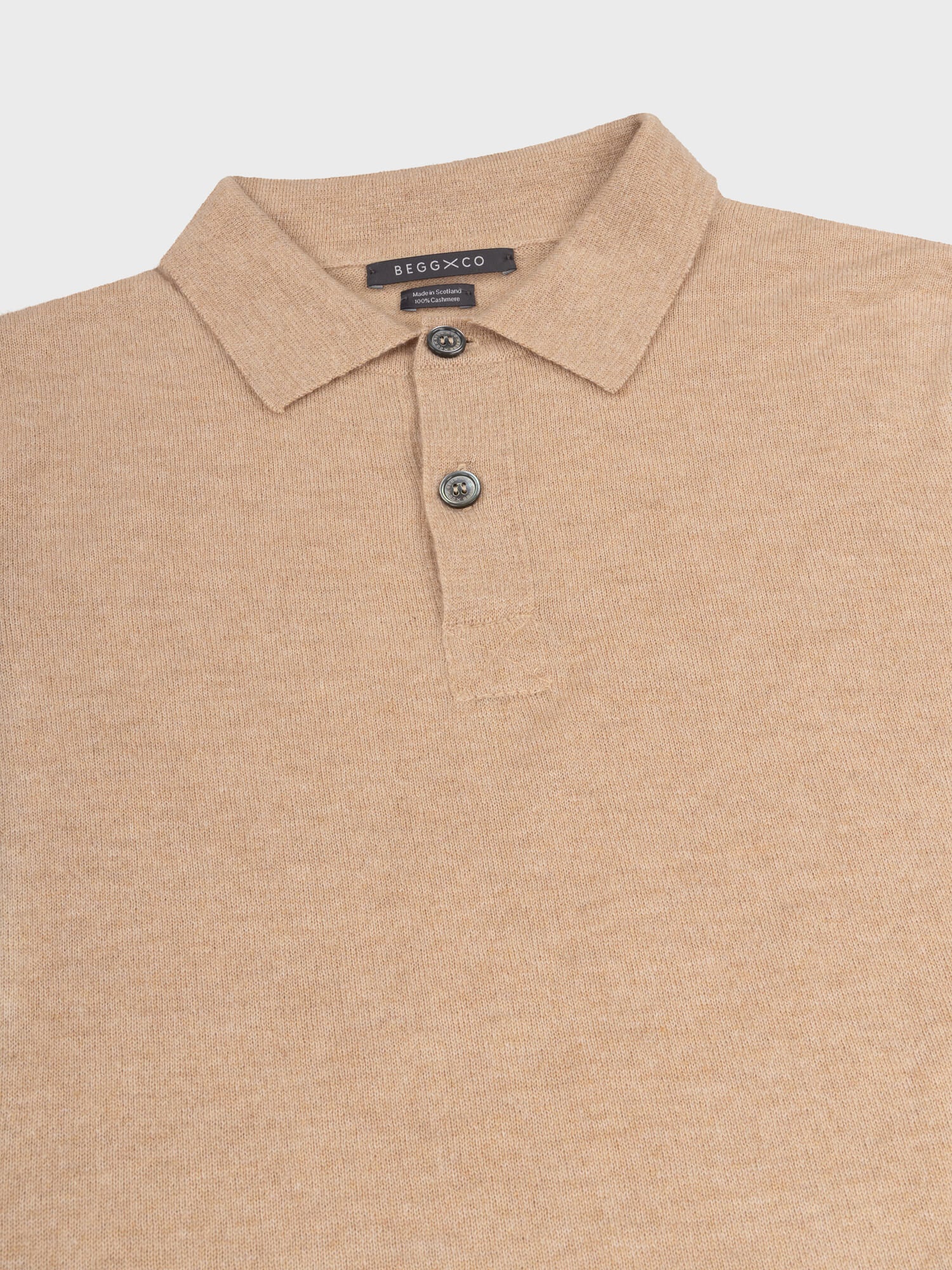 collar detail of a beige cashmere short sleeve polo on a grey background