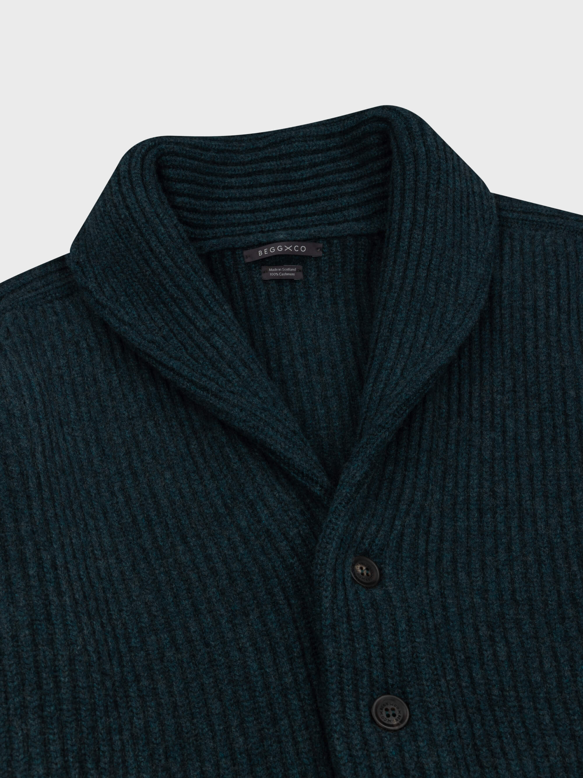 chunky ribbed dark green cashmere shawl collar cardigan on a grey background