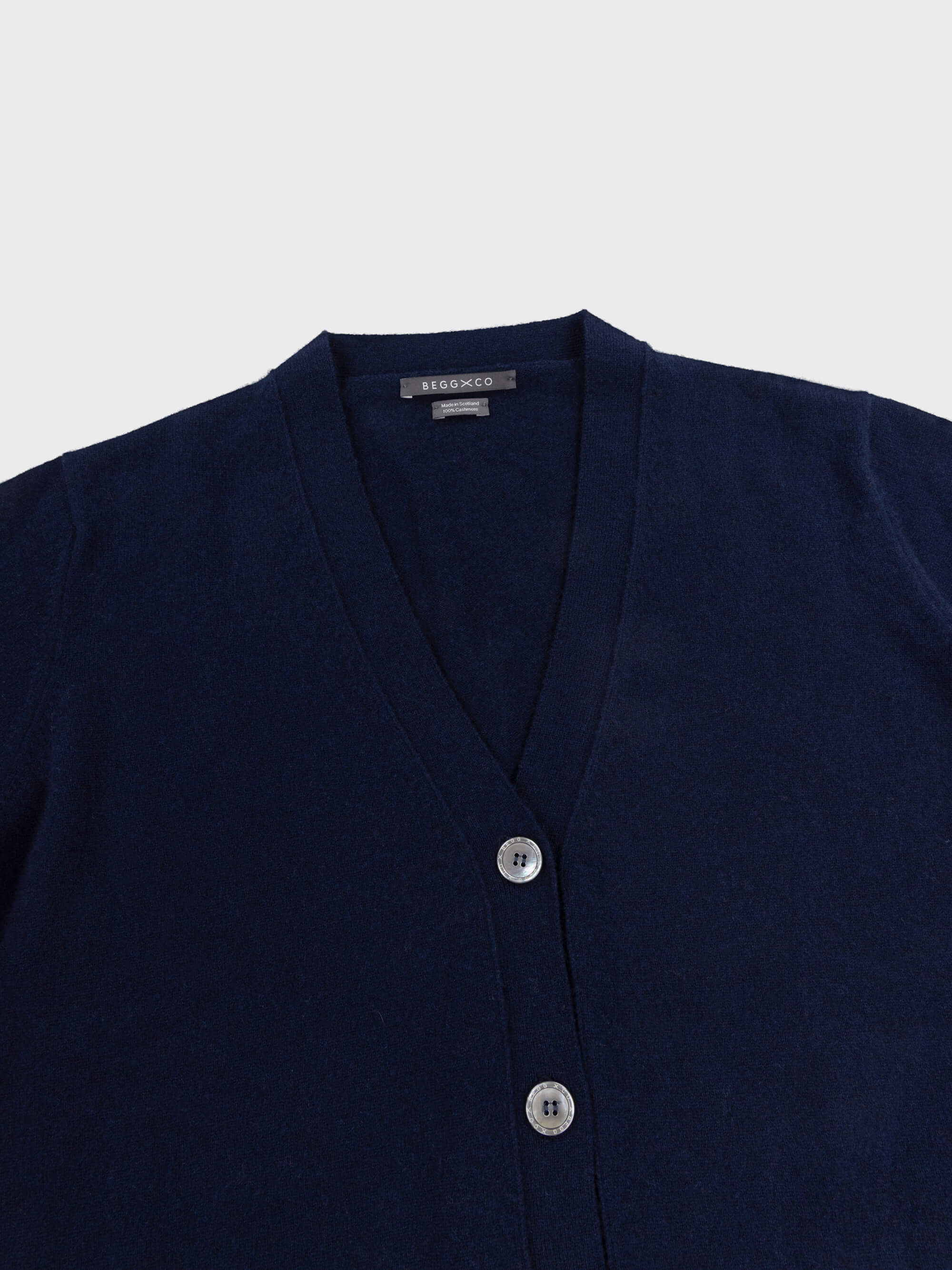 navy blue cashmere vneck cardigan with pearl buttons on a grey background
