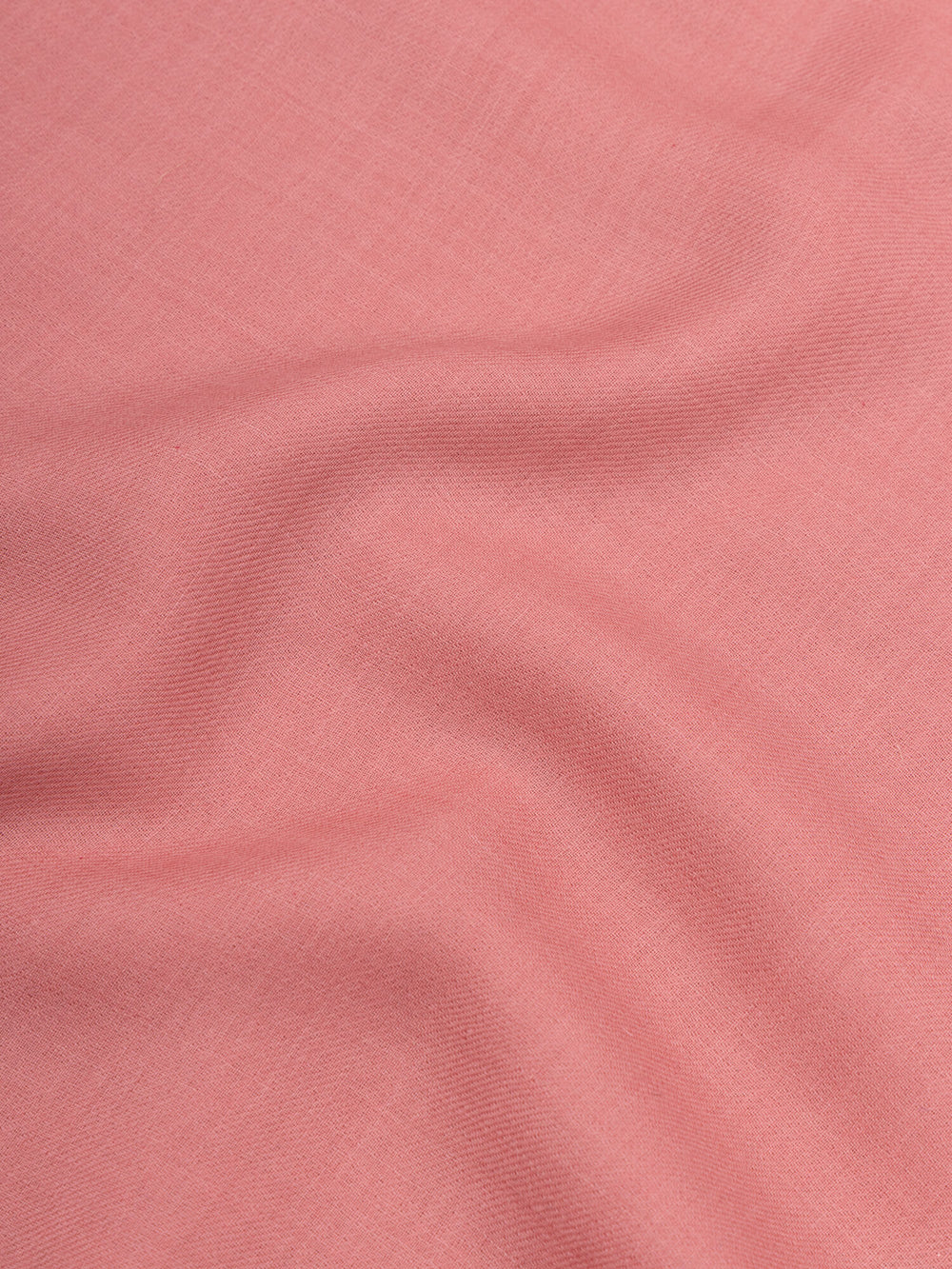 close up of a pink square cashmere scarf on a grey background