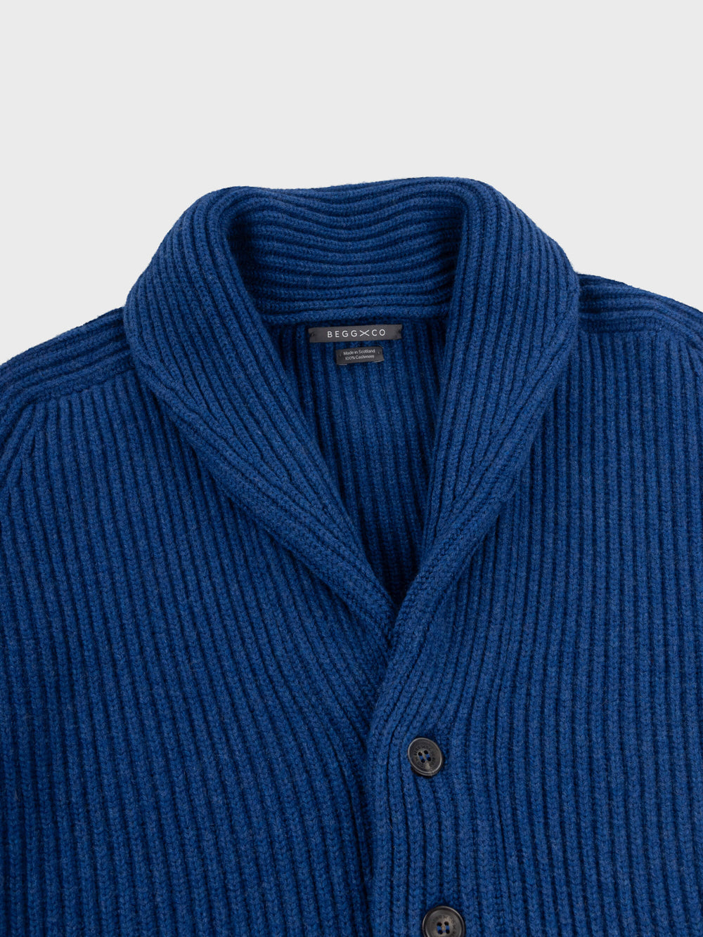 chunky ribbed blue cashmere shawl collar cardigan detail on a grey background