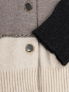 Close-up of a cashmere cardigan with buttons and a black sleeve.
