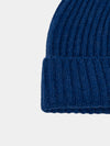 Close-up of a blue knitted cashmere beanie on a light gray background
