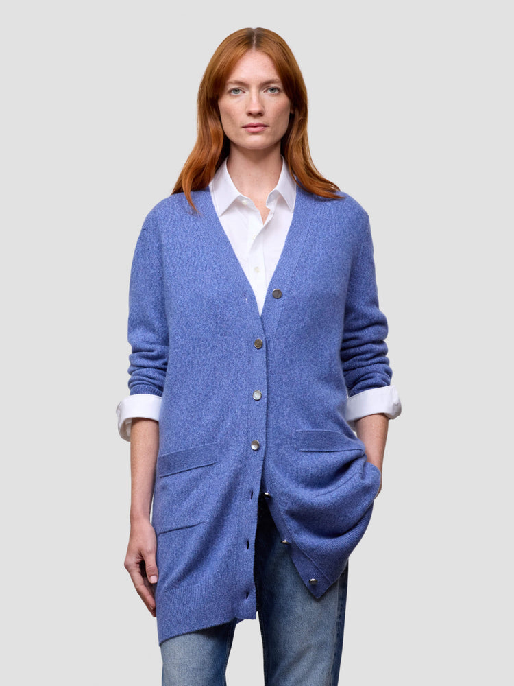 Woman wearing a blue cardigan over a white shirt on a light gray background