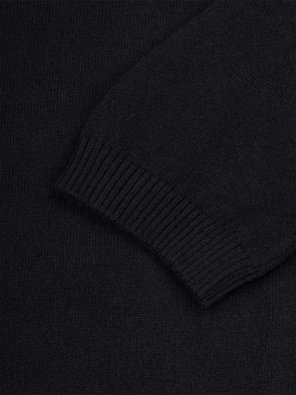 Close-up of a black cashmere t-shirt sleeve with ribbed texture.