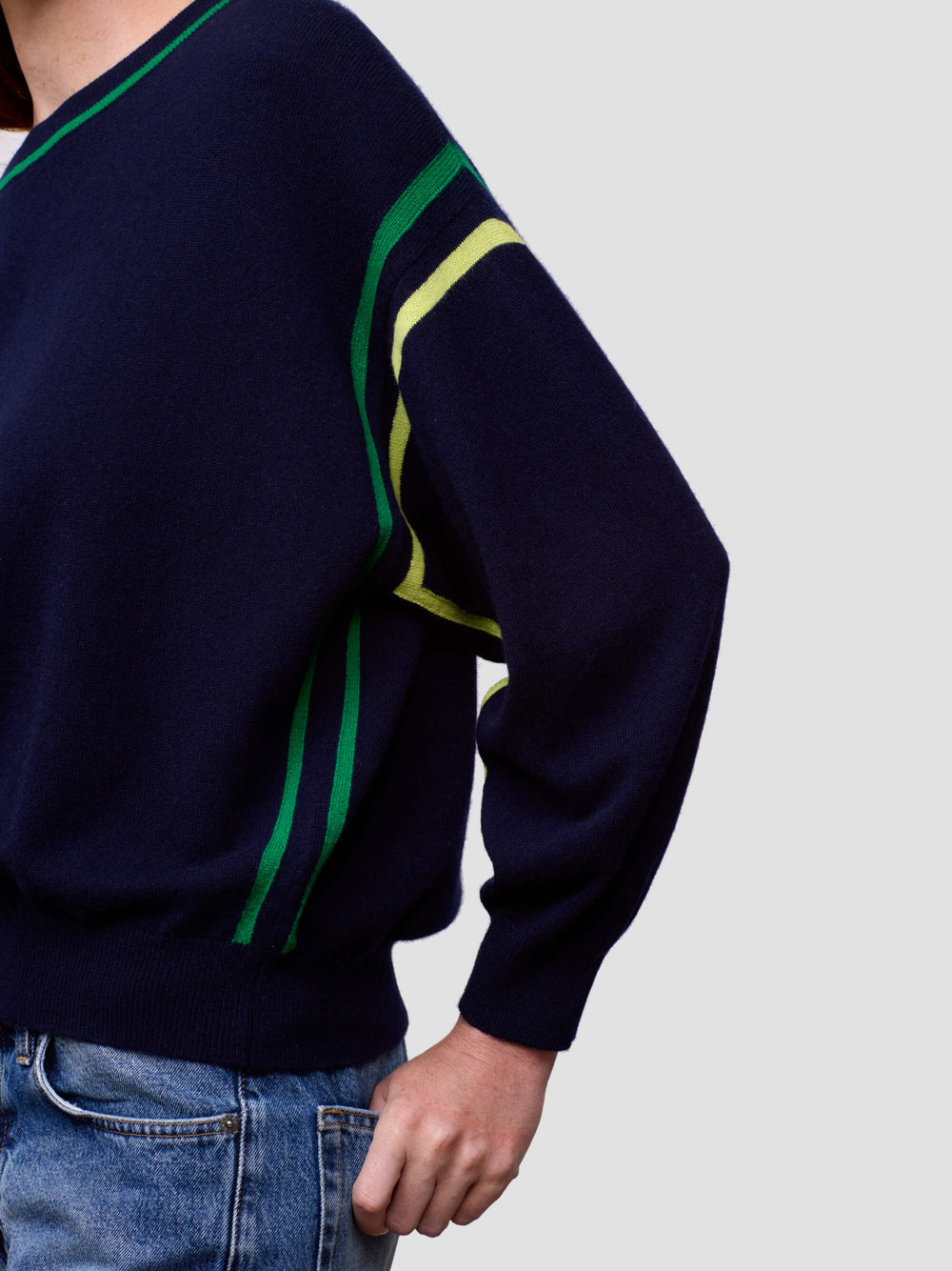 Navy sweater with green and yellow stripes on a plain background