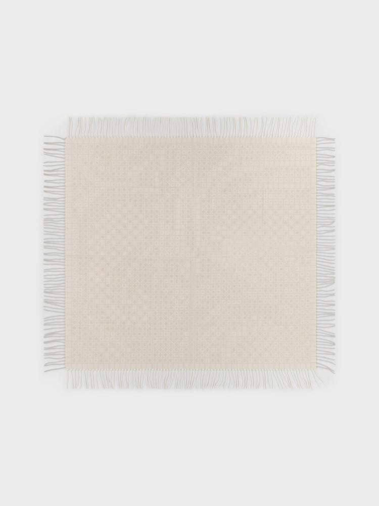 A square woven cashmere wrap in a light cream or off-white color with fringed edges, displayed flat against a solid light gray background.