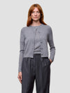 Woman wearing a gray cashmere cardigan and dark pants on a light gray background