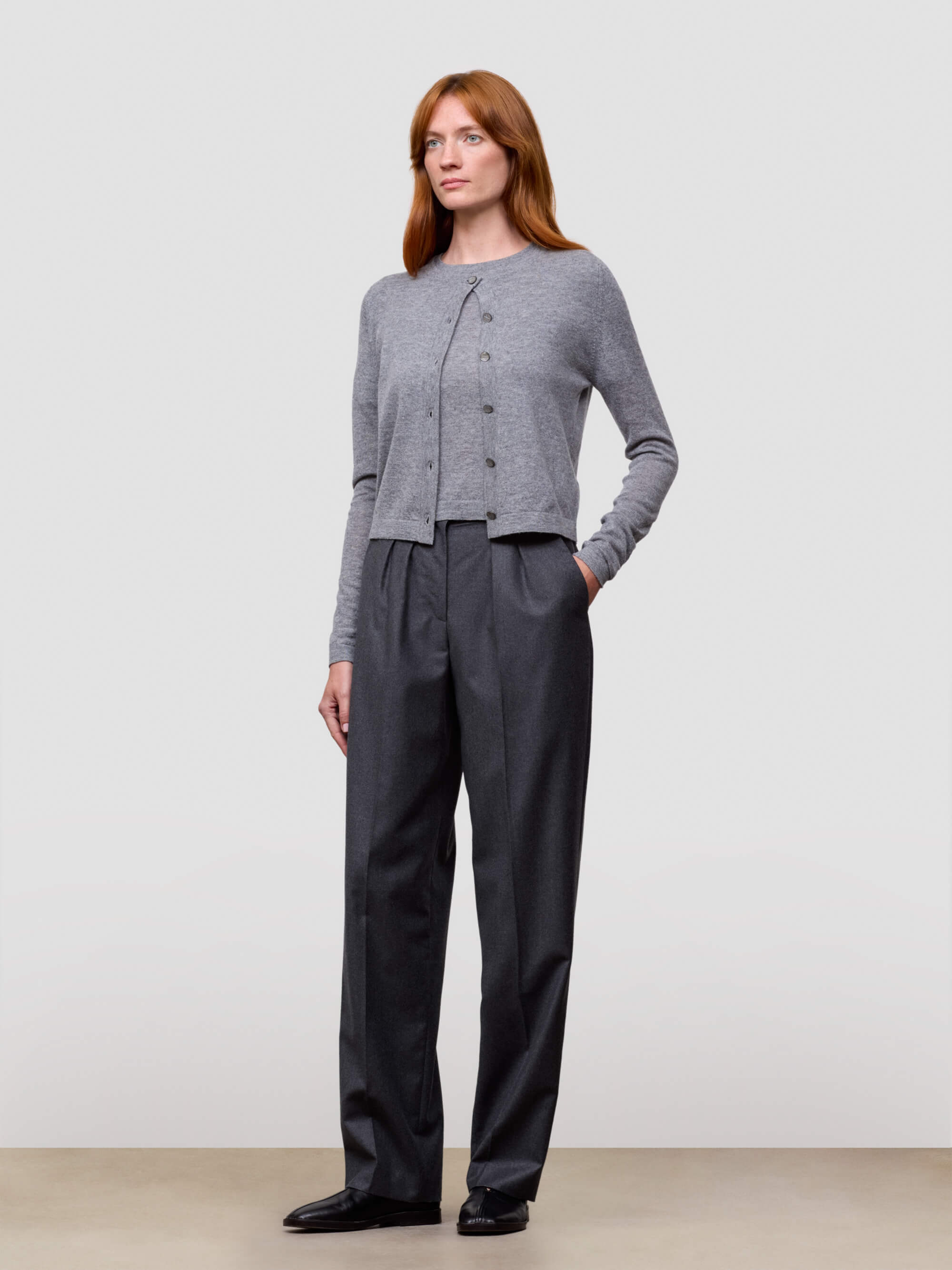 woman wearing grey cashmere cardigan and grey trousers on a white background