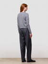 Person wearing a gray cardigan and dark pants against a white background