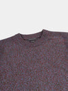 Close-up of a patterned cashmere sweater with a brand label on a light gray background