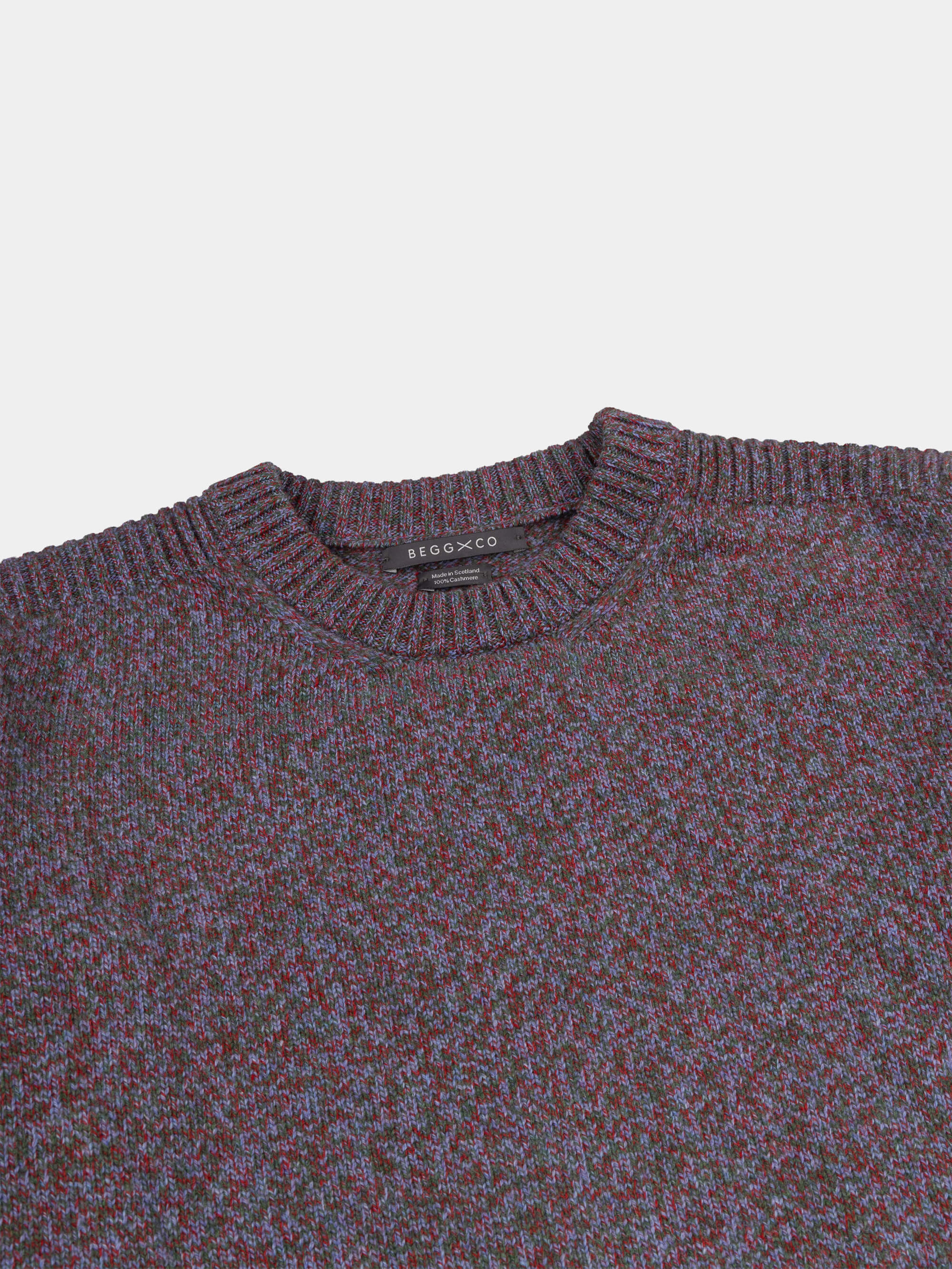 Close-up of a patterned cashmere sweater with a brand label on a light gray background