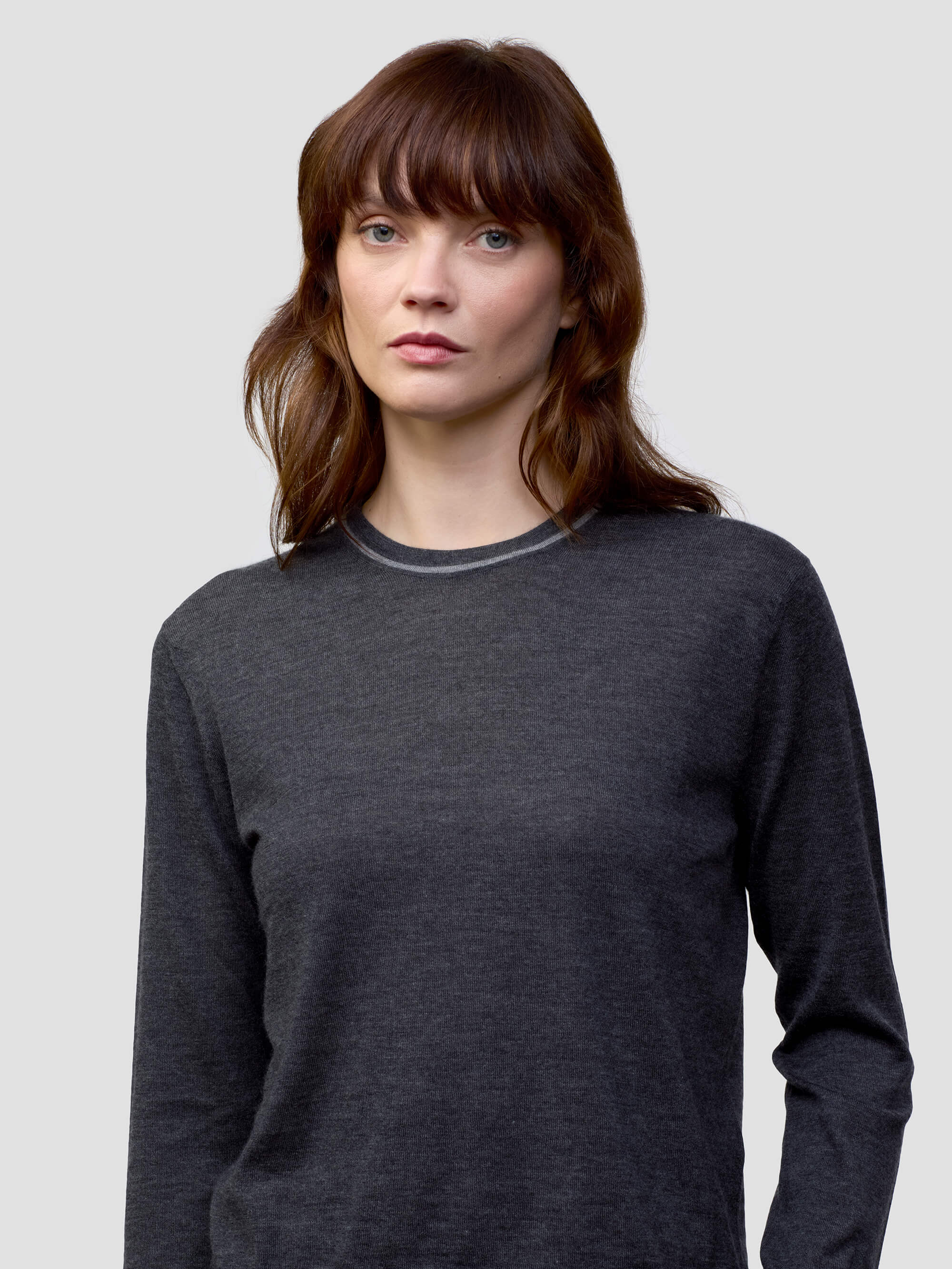 Woman wearing a dark gray cashmere sweater and light gray cashmere pants on a white background