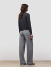 Woman wearing a dark gray cashmere sweater and light gray cashmere pants on a white background