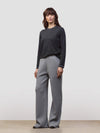 Woman wearing a dark gray cashmere sweater and light gray cashmere pants on a white background