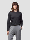 Woman wearing a dark gray cashmere sweater and light gray cashmere pants on a white background