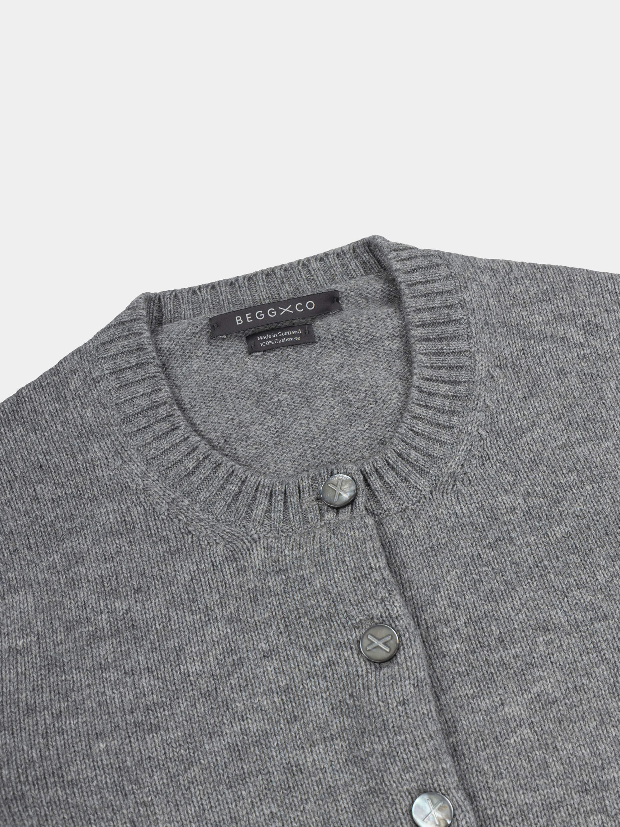 Gray cardigan with button details and Begg x Co label on a light gray background