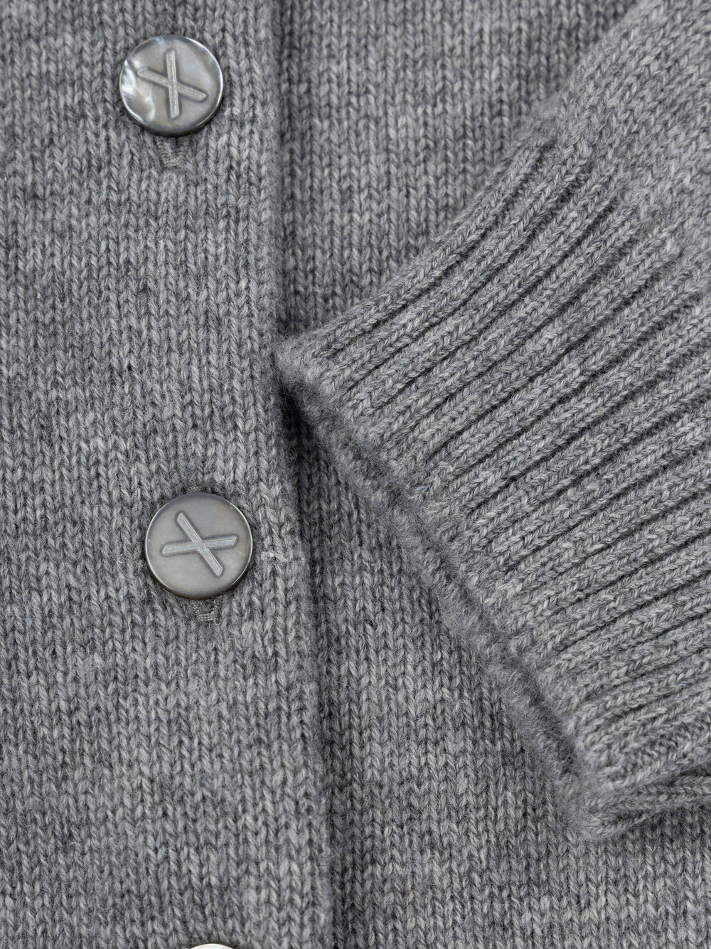 Close-up of a gray knitted cardigan with buttons on a plain background