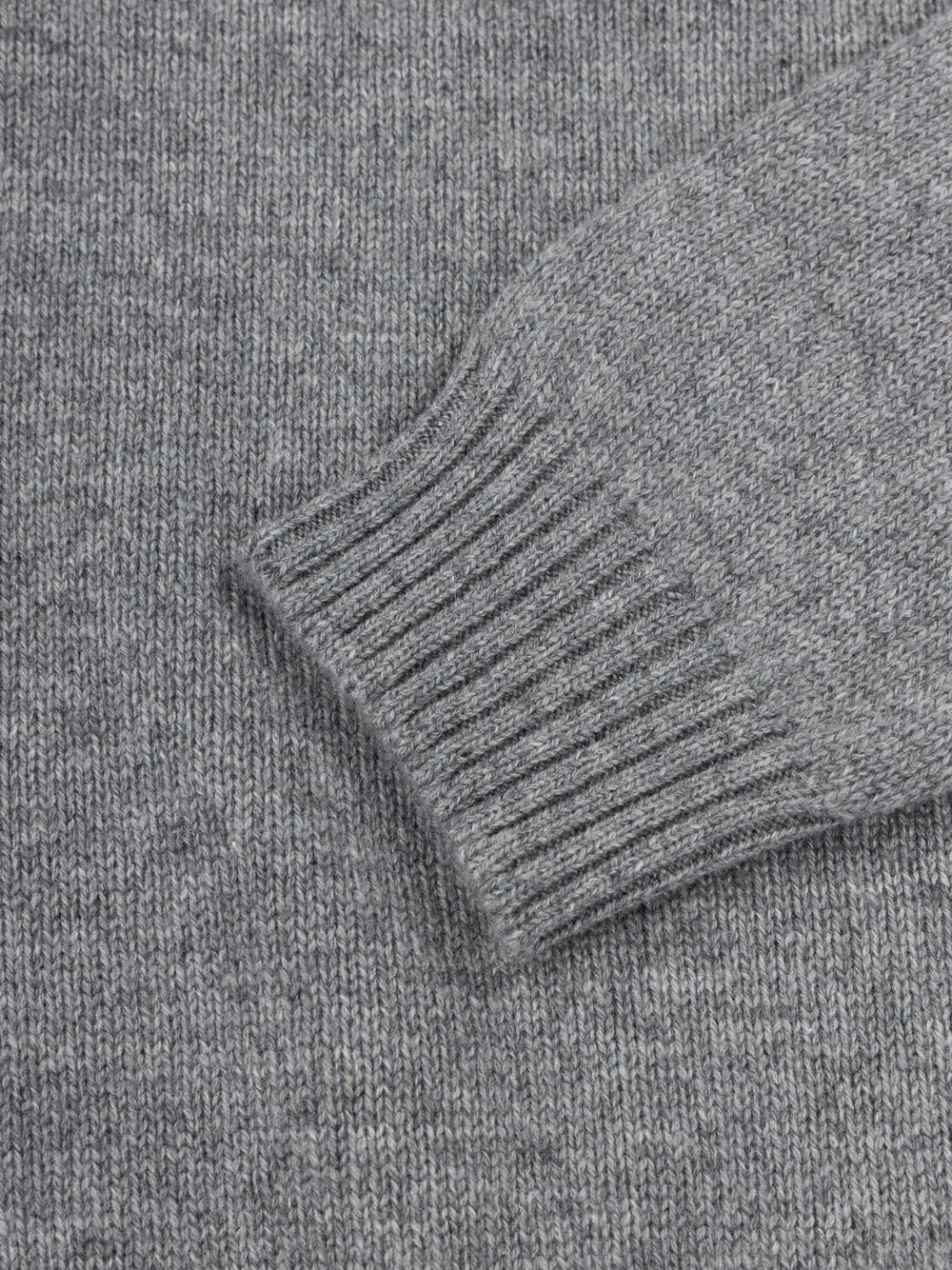Close-up of a gray cashmere sweater with ribbed cuffs and hem.