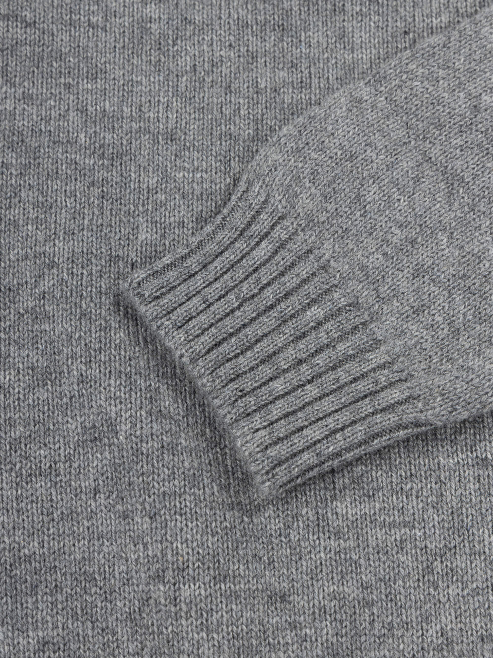 Close-up of a gray cashmere sweater with ribbed cuffs and hem.