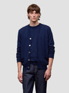 Man wearing a navy blue cardigan over a dark shirt with matching pants on a light gray background