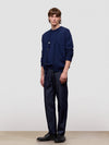 Man wearing a navy blue cardigan and pants against a plain background