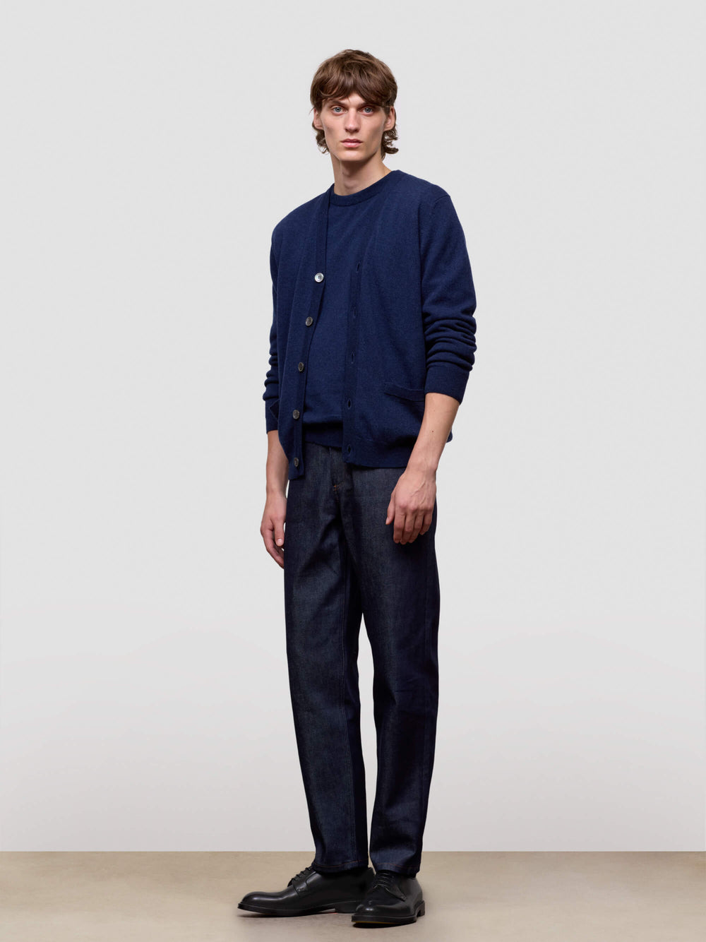 Man wearing a navy blue cardigan and pants against a plain background