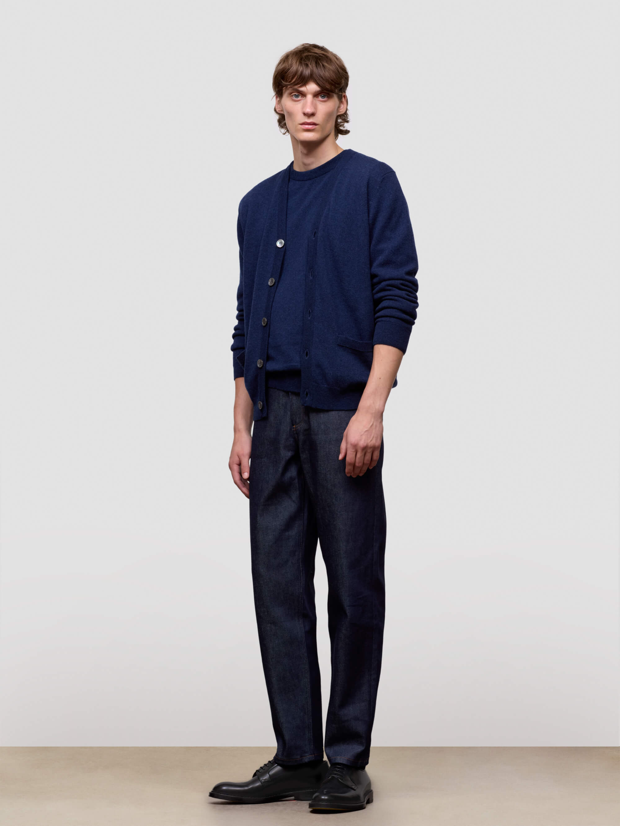 Man wearing a navy blue cardigan and pants against a plain background