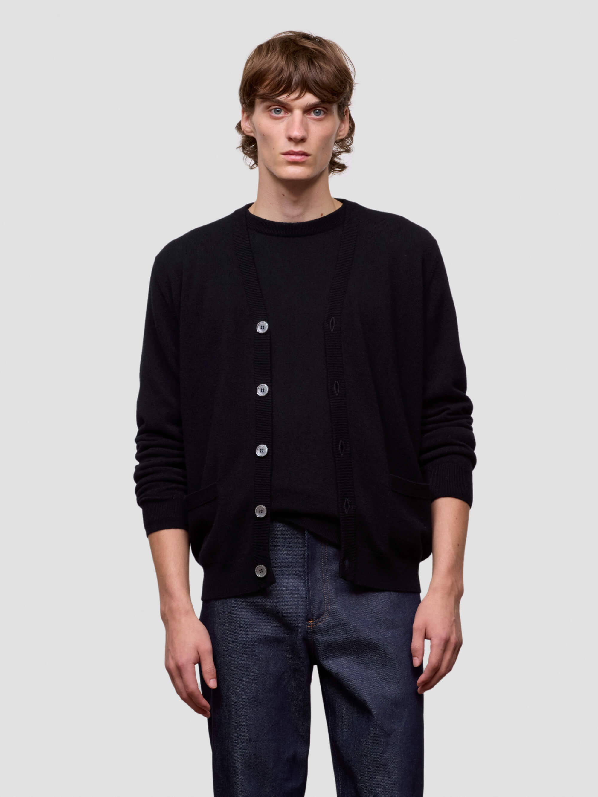 Person wearing a black button-up shirt and dark pants on a light gray background