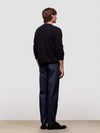 Person wearing a black sweater and dark pants against a white background
