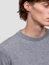 Close-up of a person wearing a gray sweater against a light gray background