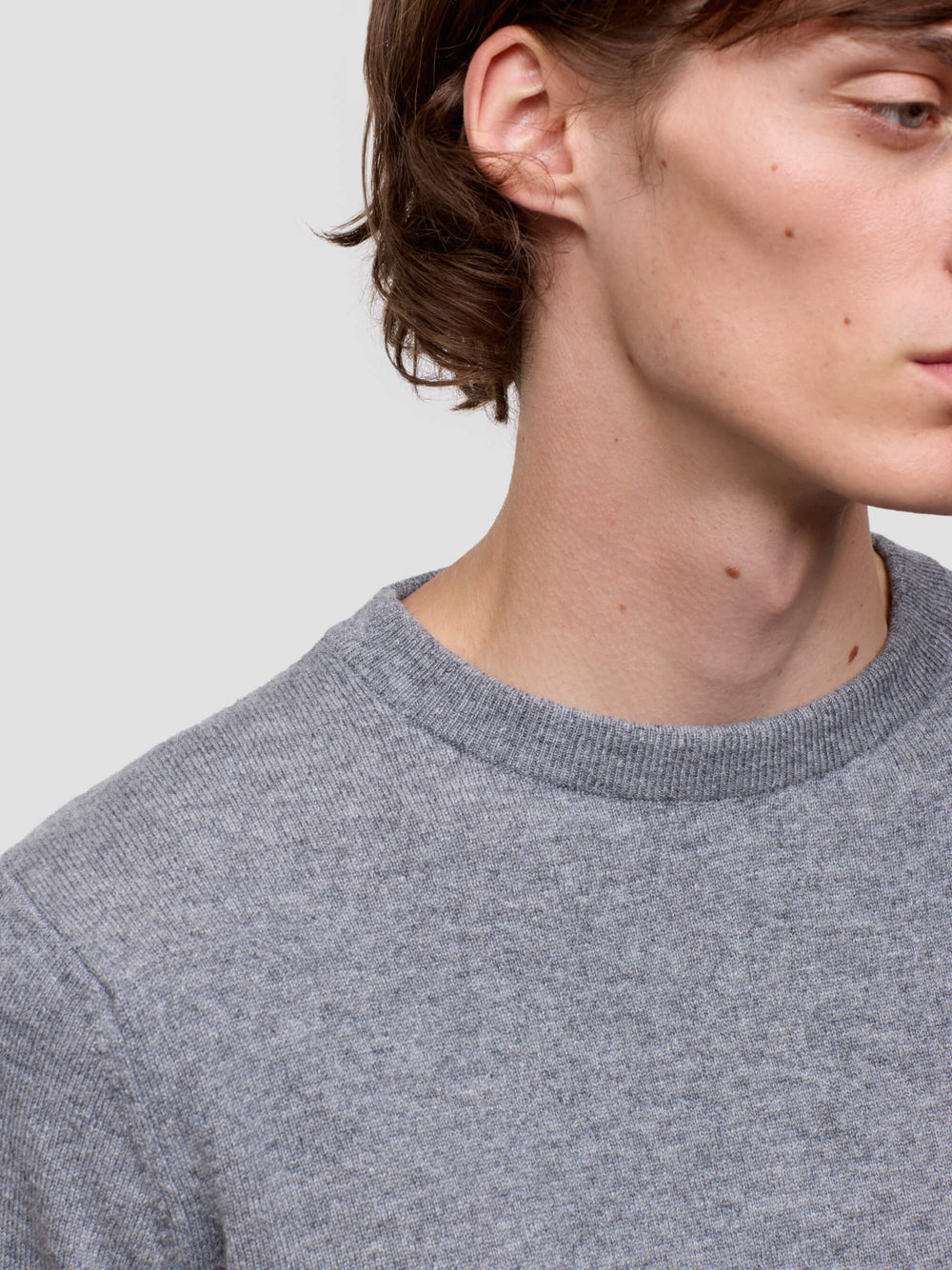 Close-up of a person wearing a gray sweater against a light gray background
