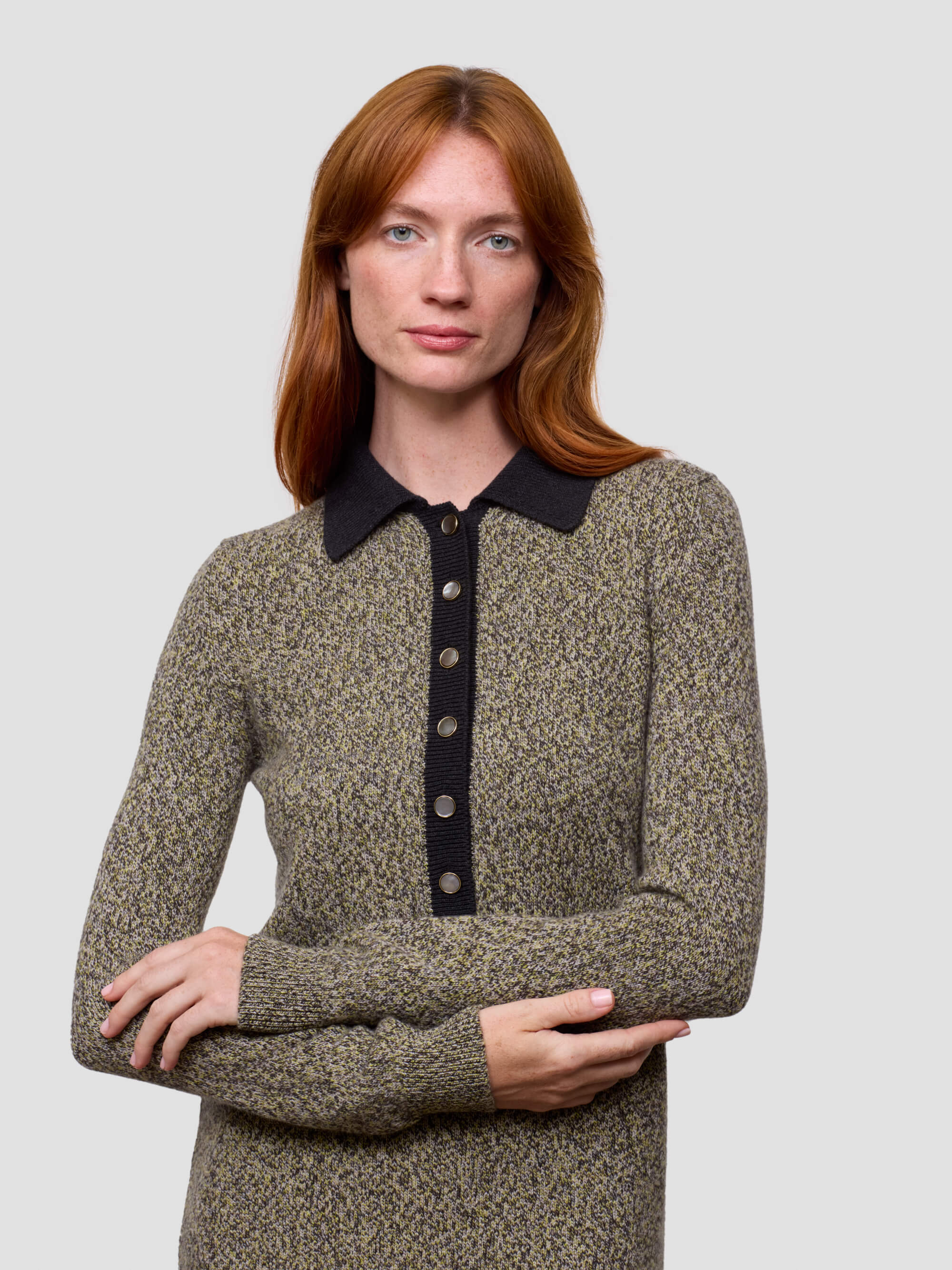 Woman wearing a patterned sweater dress with a black collar against a light gray background