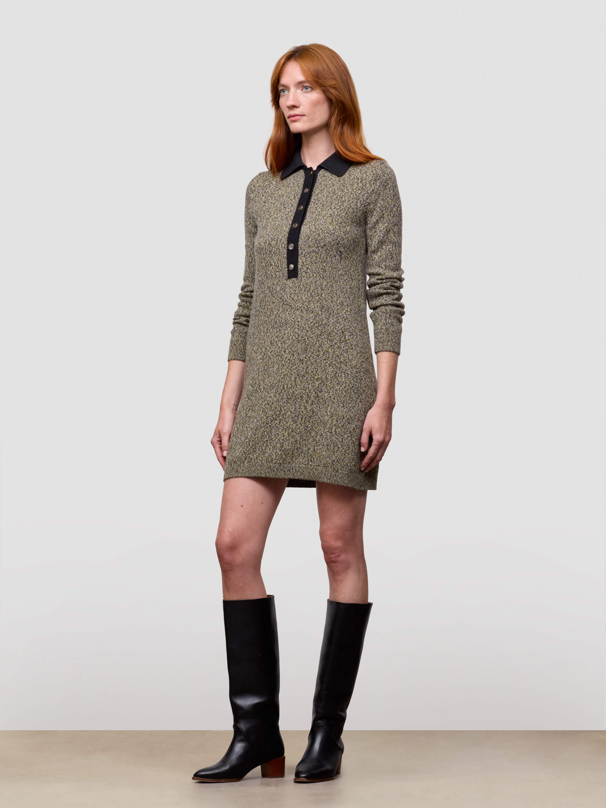 woman wearing green cashmere sweater dress with boots on plain background