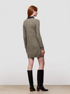 woman wearing a green cashmere sweater dress and boots on a plain background