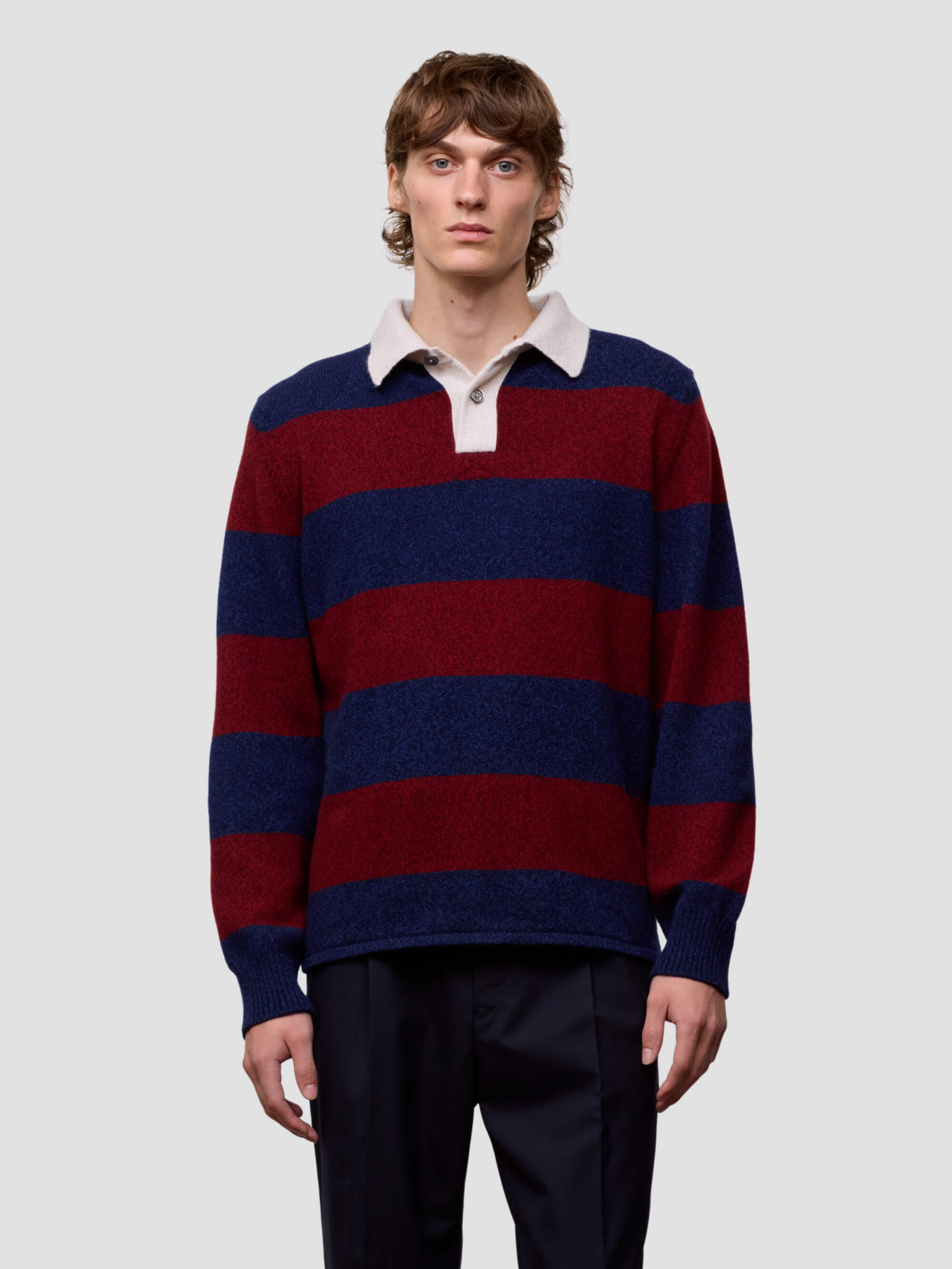 Man wearing a red and blue striped cashmere sweater over a white shirt on a light gray background