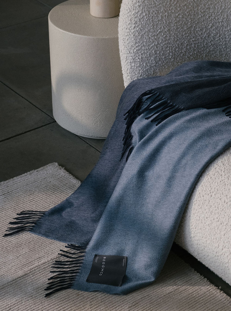 reversible blue and dark blue cashmere throw draped on a beige boucle sofa