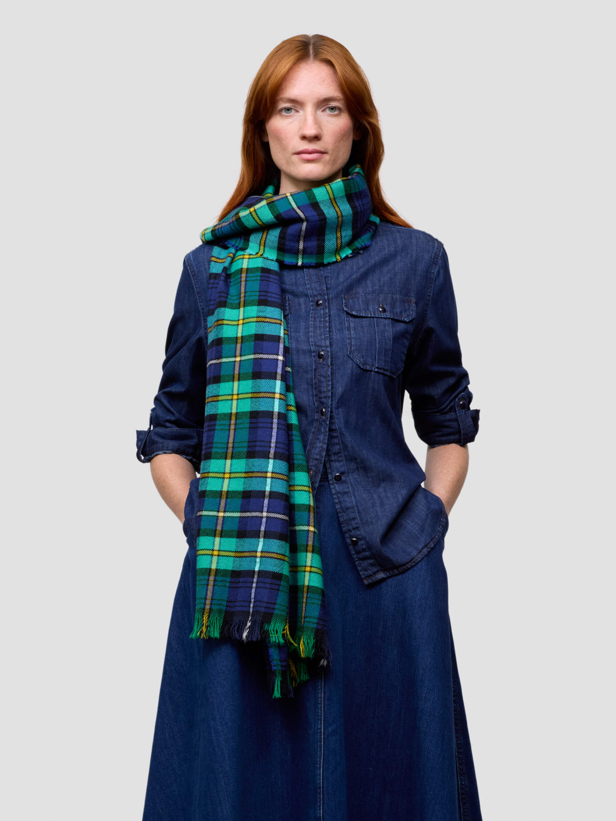 Woman wearing a blue plaid scarf over a denim shirt on a light gray background