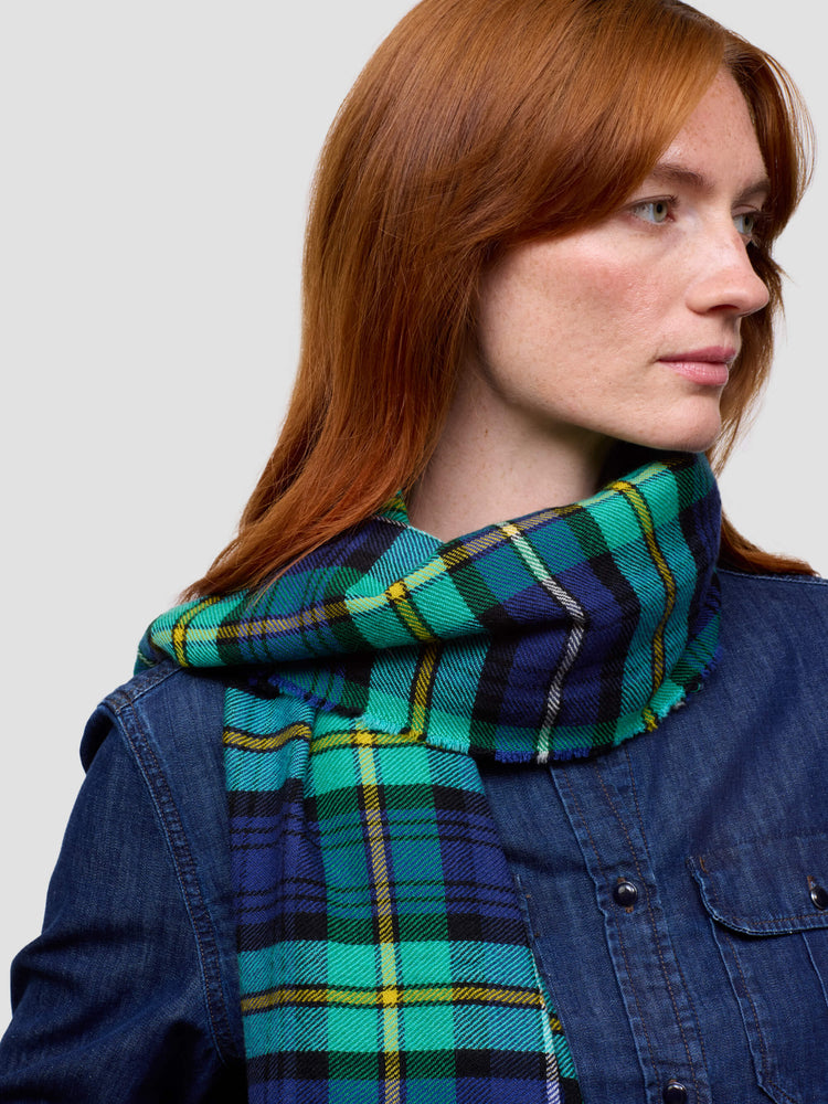 Woman wearing a green and blue plaid scarf against a plain background