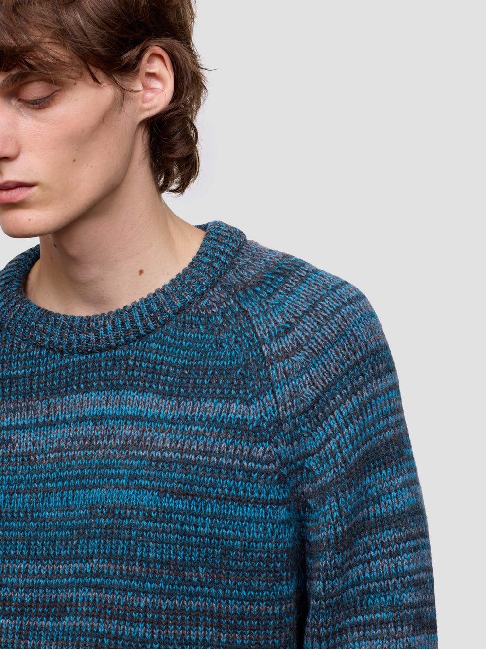 man wearing a blue and gray patterned cashmere sweater on a plain background