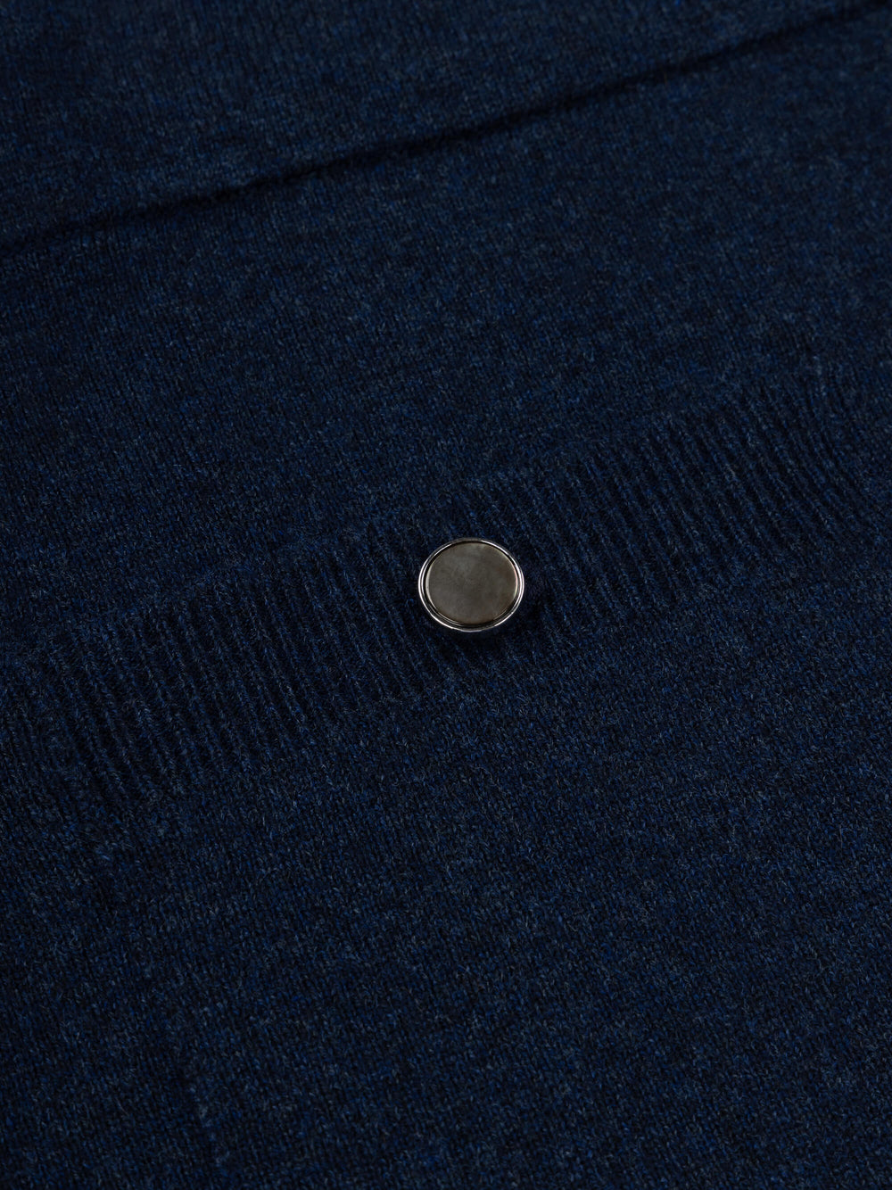 Close-up of a navy blue cashmere skirt with a button on a dark background