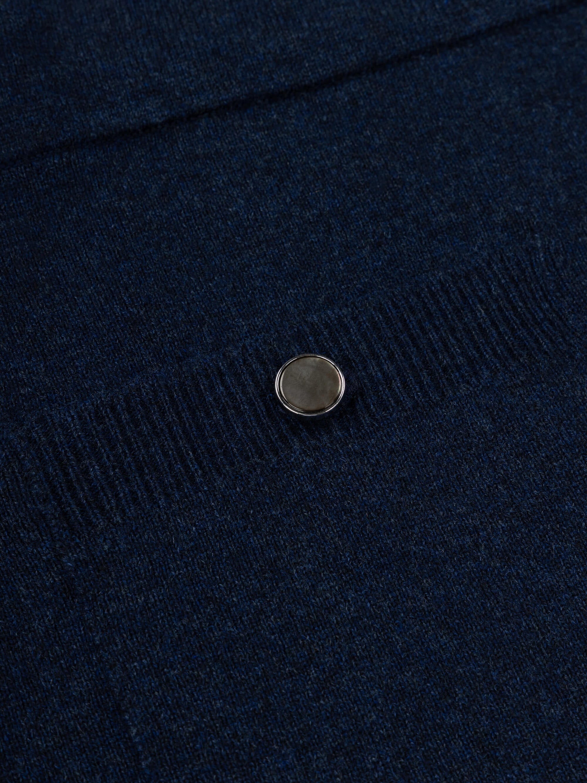 Close-up of a navy blue cashmere skirt with a button on a dark background