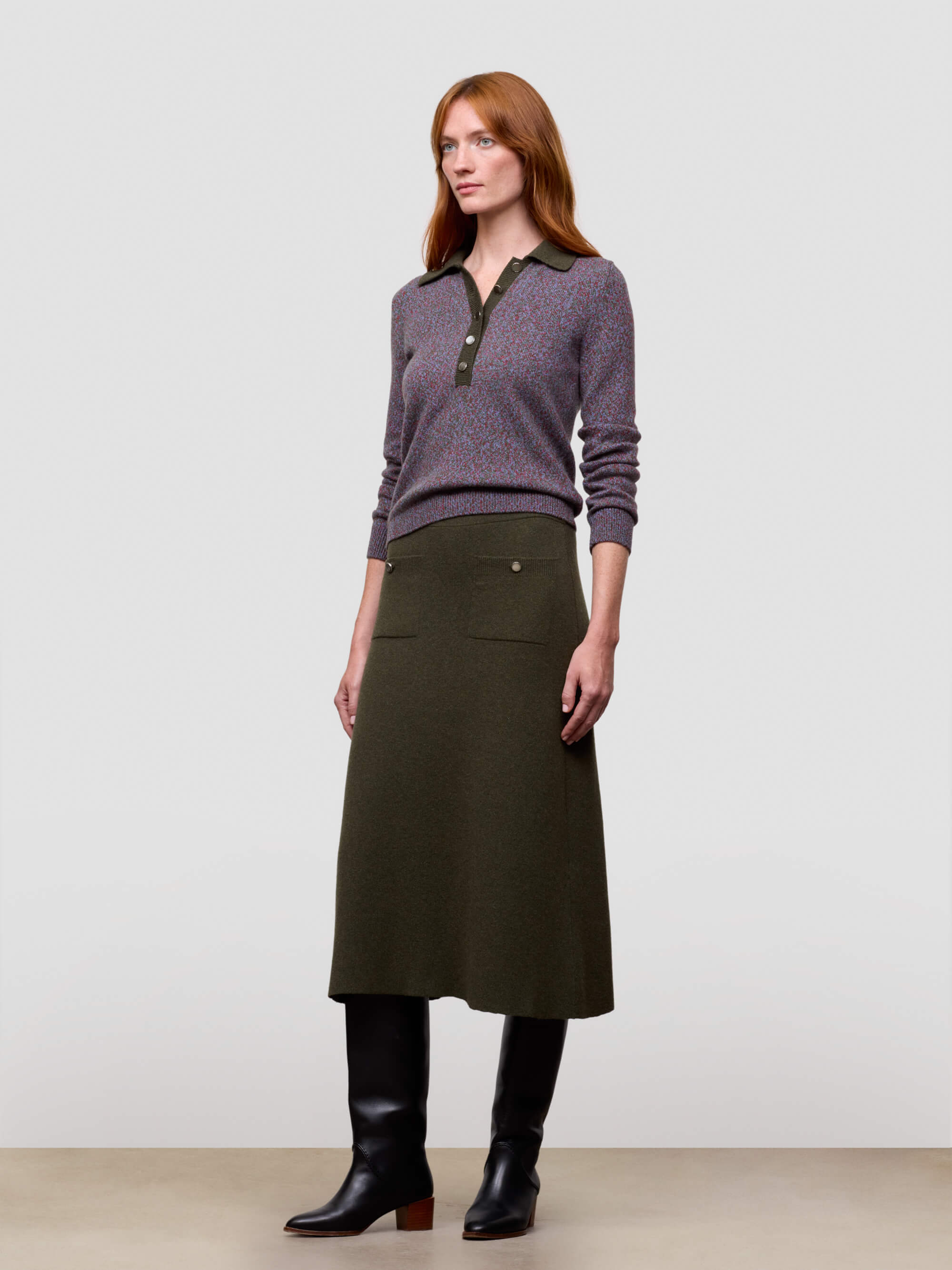 woman wearing green cashmere skirt and boots with a purple sweater