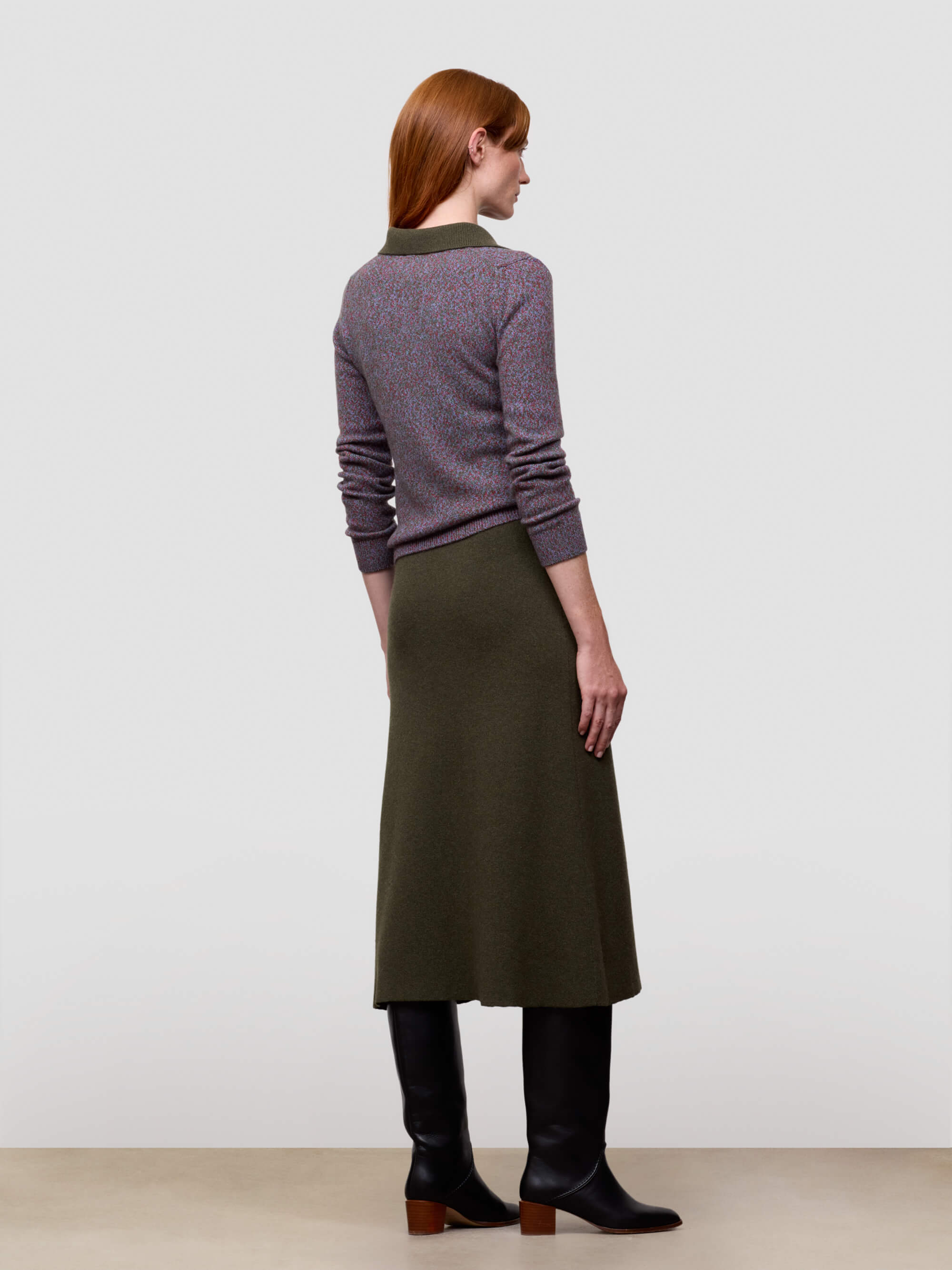 woman wearing green cashmere skirt and boots with a purple sweater
