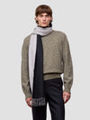 Man wearing a patterned sweater and scarf on a plain background