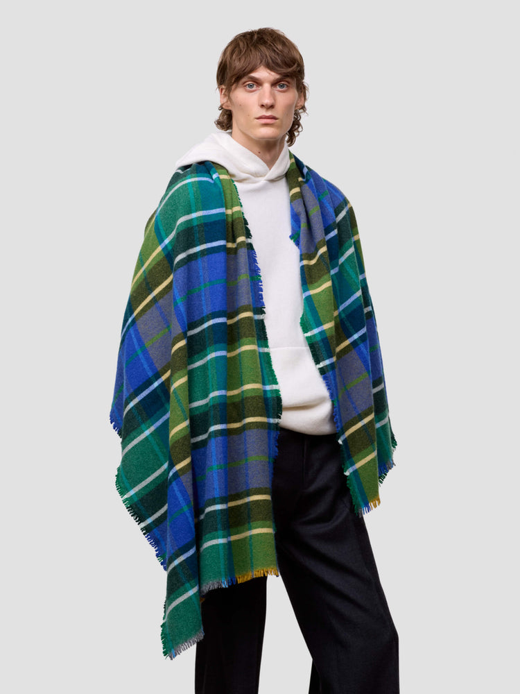 man wearing a white cashmere hoodie and a checked green and blue stole on a plain background